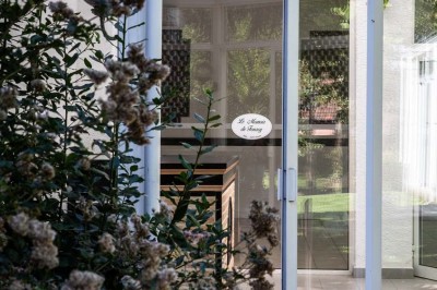 Salle de réception lumineuse avec tables dressées, lustres suspendus et nappes blanches sur des tables latérales.