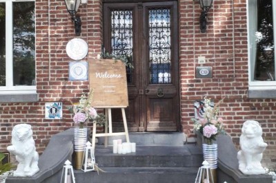 Salle de réception lumineuse avec tables dressées, lustres suspendus et nappes blanches sur des tables latérales.