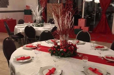 Salle de réception lumineuse avec tables dressées, lustres suspendus et nappes blanches sur des tables latérales.