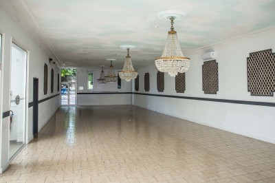 Entrée élégante avec un sol en mosaïque, un lustre en cristal, deux vases décoratifs et une statue en bois.