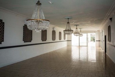 Entrée élégante avec un sol en mosaïque, un lustre en cristal, deux vases décoratifs et une statue en bois.