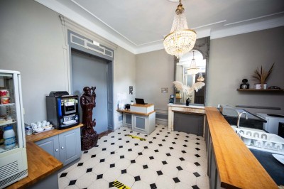 Entrée élégante avec un sol en mosaïque, un lustre en cristal, deux vases décoratifs et une statue en bois.