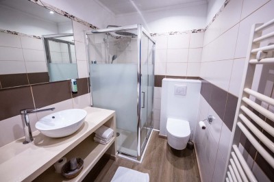 Entrée élégante avec un sol en mosaïque, un lustre en cristal, deux vases décoratifs et une statue en bois.