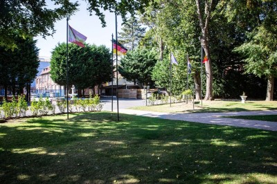 Entrée élégante avec un sol en mosaïque, un lustre en cristal, deux vases décoratifs et une statue en bois.