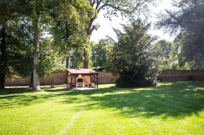 Entrée élégante avec un sol en mosaïque, un lustre en cristal, deux vases décoratifs et une statue en bois.