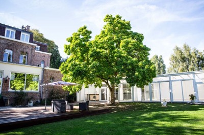 Entrée élégante avec un sol en mosaïque, un lustre en cristal, deux vases décoratifs et une statue en bois.