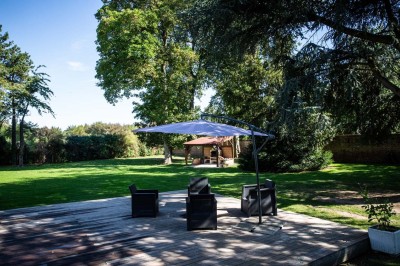 Entrée élégante avec un sol en mosaïque, un lustre en cristal, deux vases décoratifs et une statue en bois.