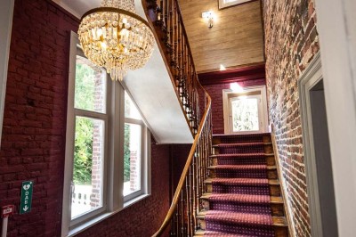 Entrée élégante avec un sol en mosaïque, un lustre en cristal, deux vases décoratifs et une statue en bois.