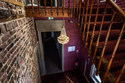 Entrée élégante avec un sol en mosaïque, un lustre en cristal, deux vases décoratifs et une statue en bois.