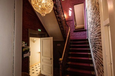 Entrée élégante avec un sol en mosaïque, un lustre en cristal, deux vases décoratifs et une statue en bois.