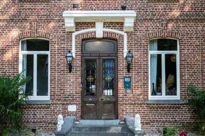 Entrée élégante avec un sol en mosaïque, un lustre en cristal, deux vases décoratifs et une statue en bois.