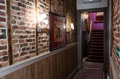 Entrée élégante avec un sol en mosaïque, un lustre en cristal, deux vases décoratifs et une statue en bois.