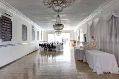 Entrée élégante avec un sol en mosaïque, un lustre en cristal, deux vases décoratifs et une statue en bois.