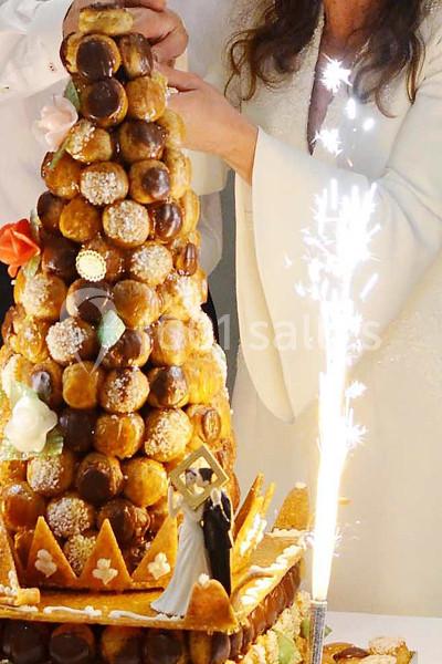 Pièce montée en choux décorée de fleurs en sucre, avec une figurine de mariage et une fontaine lumineuse allumée.