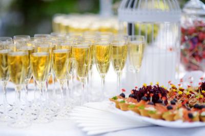 Salle lumineuse avec une grande table dressée pour un repas, décorée de fleurs et entourée de baies vitrées donnant sur un…