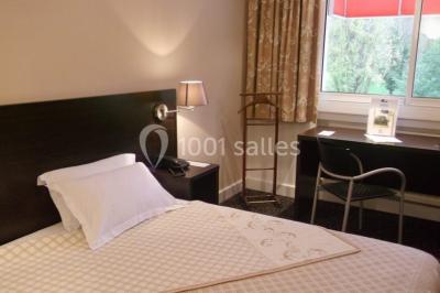 Salle lumineuse avec une grande table dressée pour un repas, décorée de fleurs et entourée de baies vitrées donnant sur un…