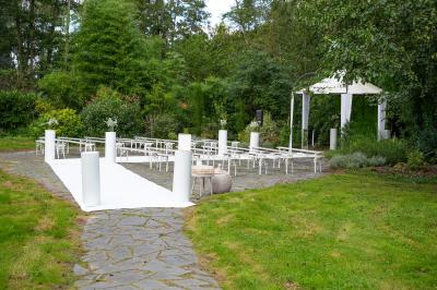 Salle lumineuse avec une grande table dressée pour un repas, décorée de fleurs et entourée de baies vitrées donnant sur un…
