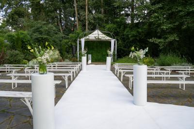 Salle lumineuse avec une grande table dressée pour un repas, décorée de fleurs et entourée de baies vitrées donnant sur un…