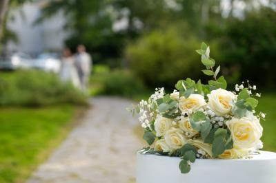 Salle lumineuse avec une grande table dressée pour un repas, décorée de fleurs et entourée de baies vitrées donnant sur un…