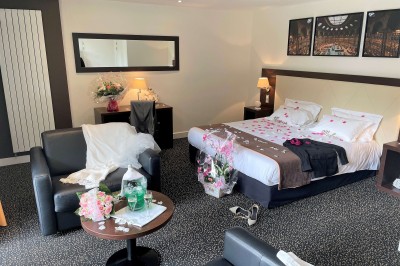 Chambre d'hôtel lumineuse avec un lit double, un bureau près d'une fenêtre et des murs partiellement violets.