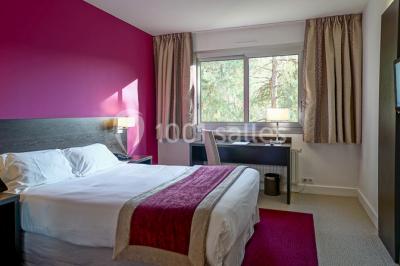 Maison blanche entourée d'arbres, avec terrasse équipée de parasols orange et mobilier de jardin en métal blanc.