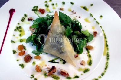 Maison blanche entourée d'arbres, avec terrasse équipée de parasols orange et mobilier de jardin en métal blanc.