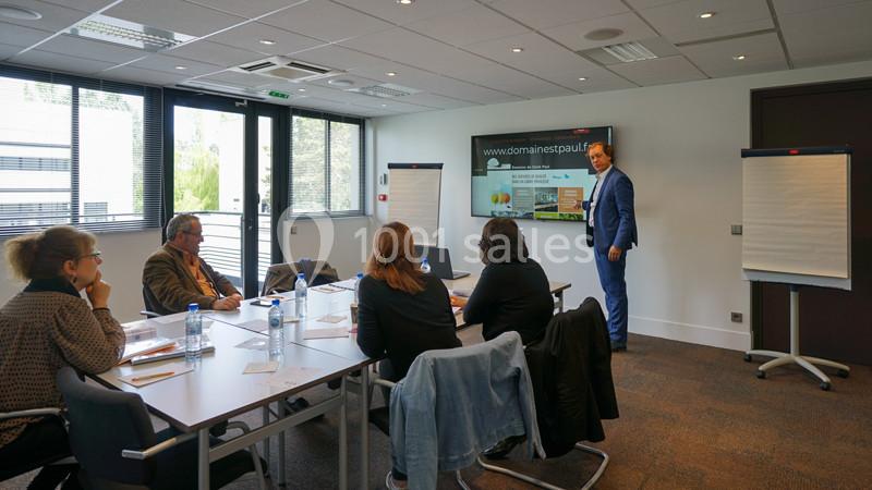 Un homme présente un diaporama à un groupe de personnes dans une salle de réunion lumineuse.