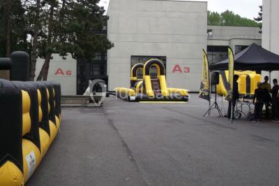 Maison blanche entourée d'arbres, avec terrasse équipée de parasols orange et mobilier de jardin en métal blanc.
