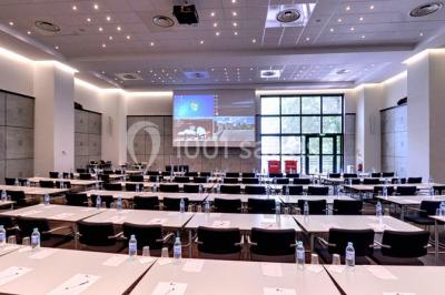 Maison blanche entourée d'arbres, avec terrasse équipée de parasols orange et mobilier de jardin en métal blanc.