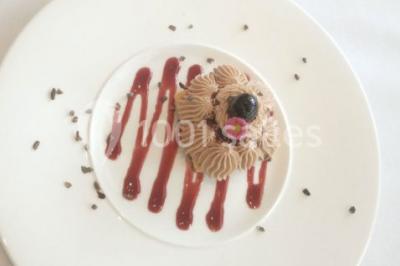 Maison blanche entourée d'arbres, avec terrasse équipée de parasols orange et mobilier de jardin en métal blanc.