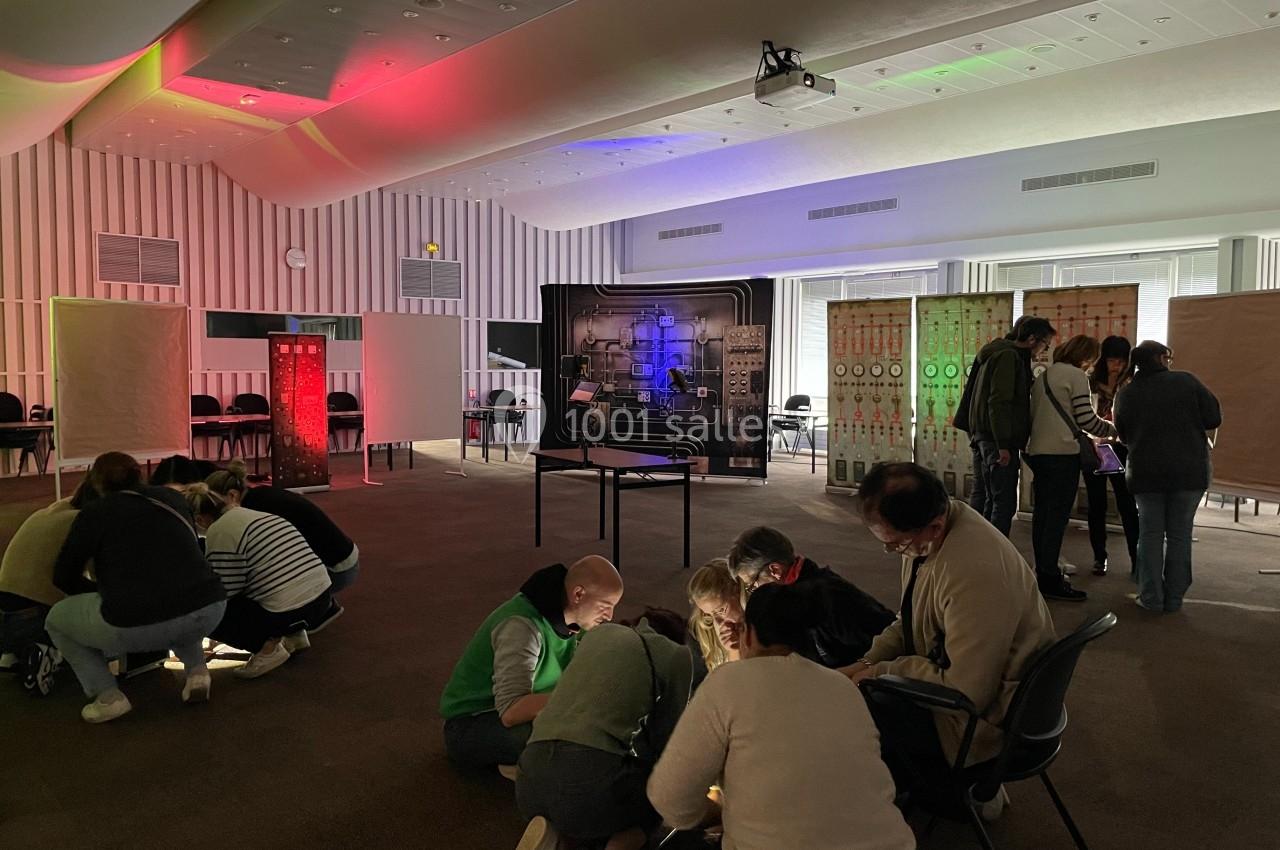 Des personnes participent à une activité collaborative dans une salle éclairée par des lumières colorées.