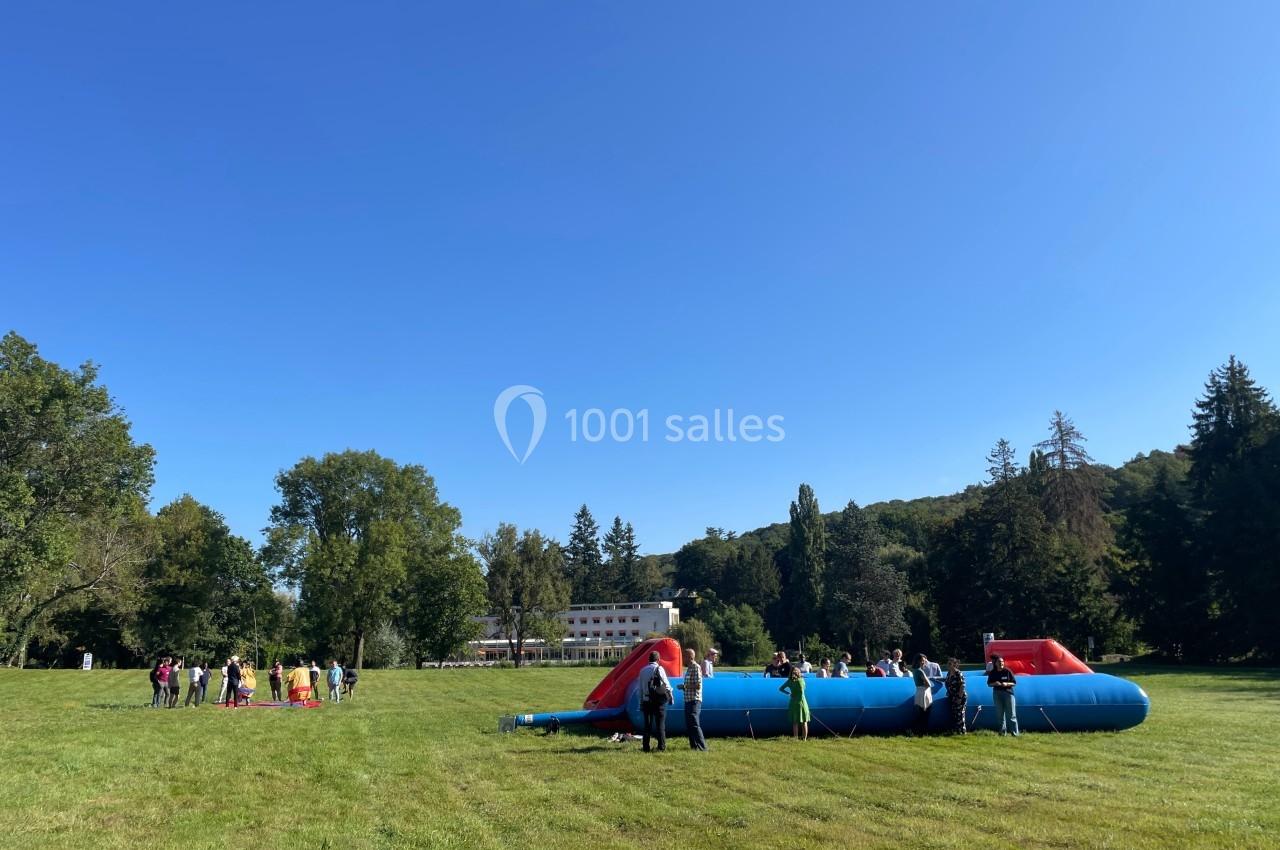Des personnes participent à des activités sur des structures gonflables dans un grand espace vert par une journée…