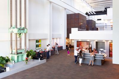 Maison blanche entourée d'arbres, avec terrasse équipée de parasols orange et mobilier de jardin en métal blanc.