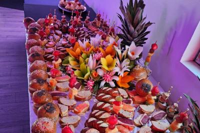 Buffet coloré avec pains, brochettes de fruits, charcuteries et décorations florales en fruits exotiques.