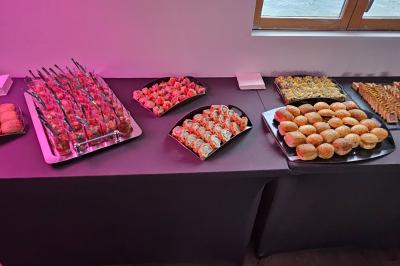 Buffet coloré avec pains, brochettes de fruits, charcuteries et décorations florales en fruits exotiques.