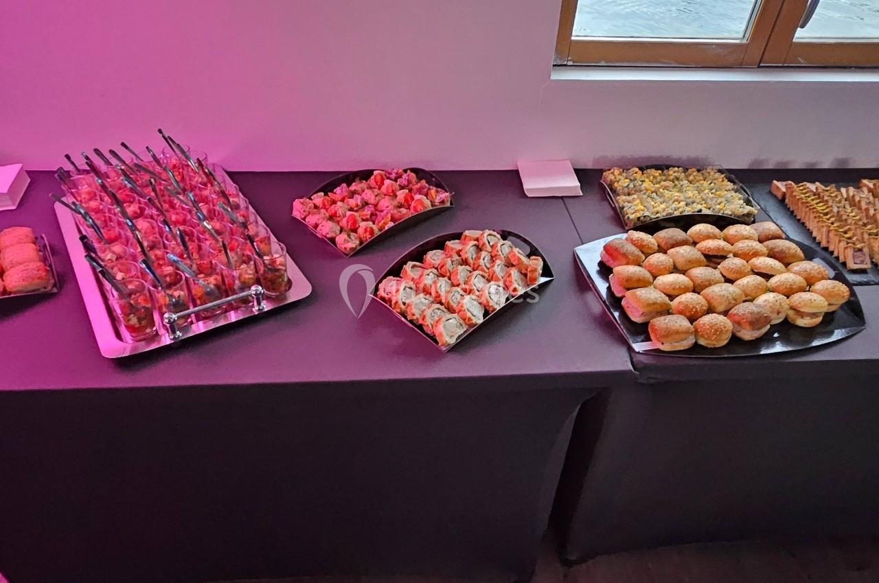 Buffet de petits fours variés disposés sur une table noire, avec des fenêtres en arrière-plan.