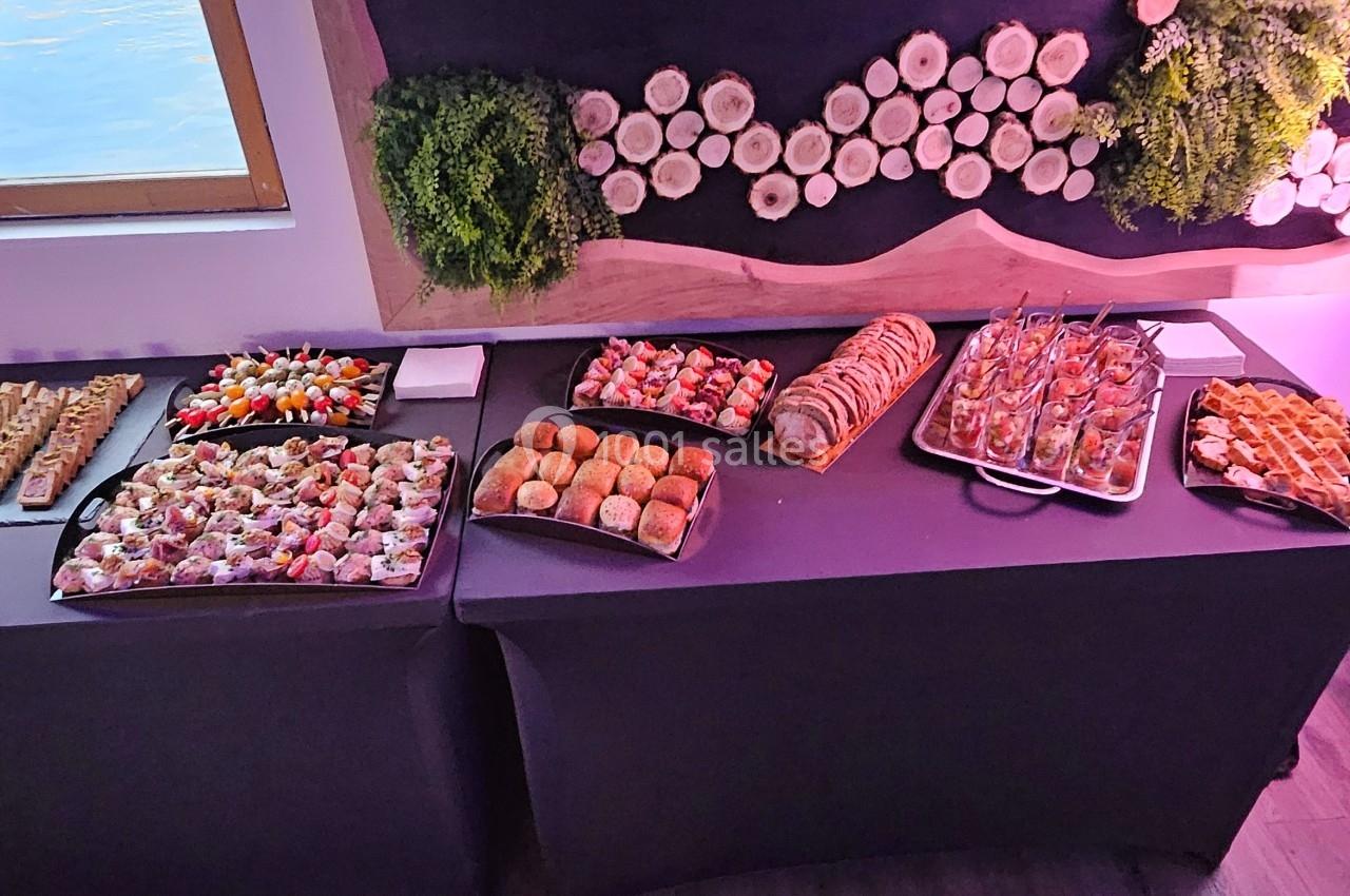 Buffet composé de divers amuse-bouches, pains et viennoiseries, disposé sur des tables devant un mur décoré.