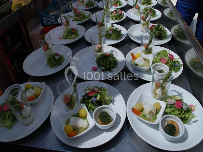 Assiettes dressées avec des salades, légumes colorés et verrines, disposées sur une table en inox.