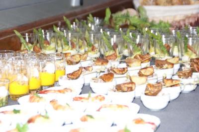 Salle lumineuse avec parquet clair, tables pliantes, chaises empilées et fenêtres laissant entrer la lumière naturelle.