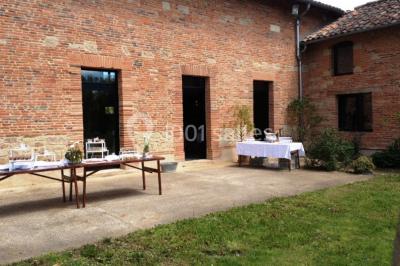 Salle spacieuse avec murs en briques, poutres apparentes, éclairage moderne et comptoirs lumineux rouges.
