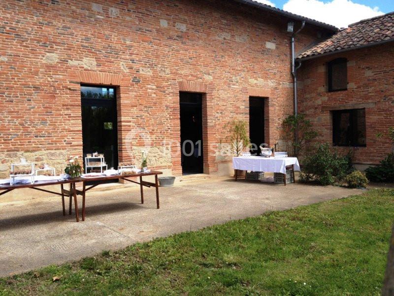 Cour d'une bâtisse en briques rouges avec tables dressées pour un événement en extérieur.