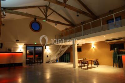 Salle spacieuse avec murs en briques, poutres apparentes, éclairage moderne et comptoirs lumineux rouges.