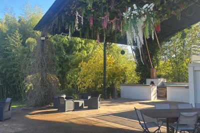 Salle spacieuse avec mezzanine, poutres apparentes, tables et chaises empilées, éclairage chaleureux.