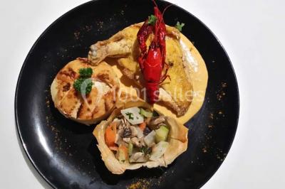 Assiette de saumon fumé avec tranches de citron vert, toasts garnis de crème et tomate, présentée sur un fond noir.