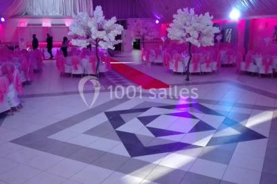 Parking vide avec marquages au sol, entouré de bâtiments industriels et d'arbres sous un ciel dégagé.