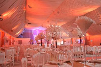 Parking vide avec marquages au sol, entouré de bâtiments industriels et d'arbres sous un ciel dégagé.
