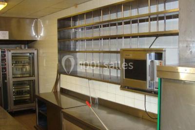 Parking vide avec marquages au sol, entouré de bâtiments industriels et d'arbres sous un ciel dégagé.