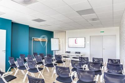 Terrasse avec des tables et chaises bleues, entourée de jardinières et d'une structure métallique végétalisée.
