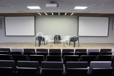 Terrasse avec des tables et chaises bleues, entourée de jardinières et d'une structure métallique végétalisée.
