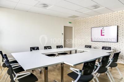 Terrasse avec des tables et chaises bleues, entourée de jardinières et d'une structure métallique végétalisée.